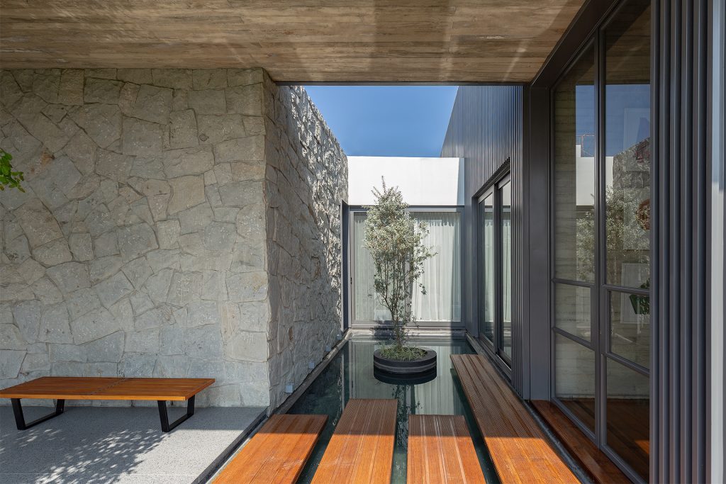 6M House – Kamnite stene in prehod ob manjšem vodnem vrtu.