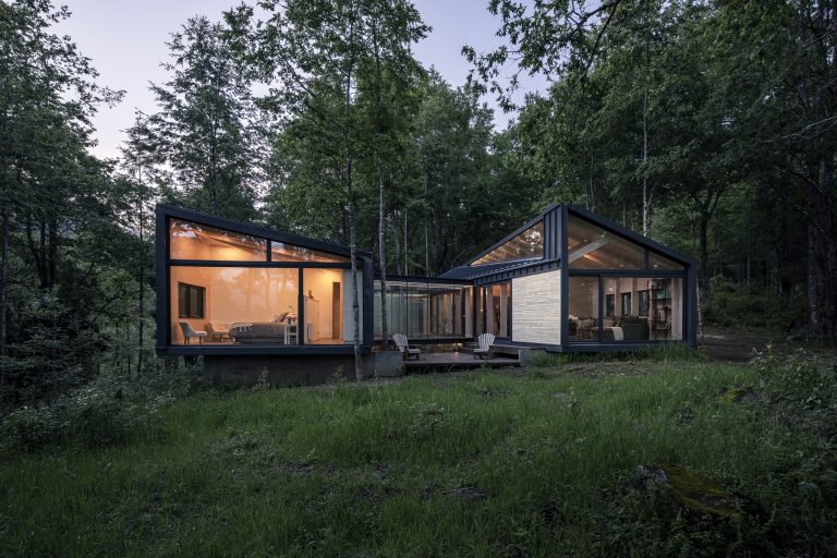 Forest House – Dva lesena volumna med drevesi ob gozdni jasi.