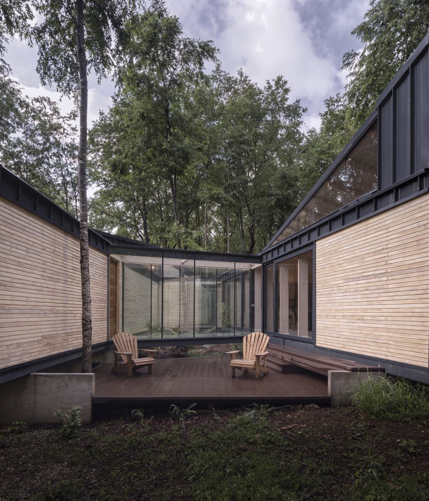 Forest House – Lesena terasa med obema deloma hiše.