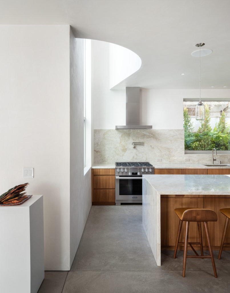 Radius House – Kuhinja s svetlimi stenami in leseno opremo.