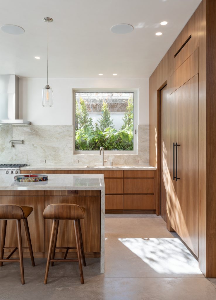 Radius House – Kuhinjski otok ob orehovih omarah.