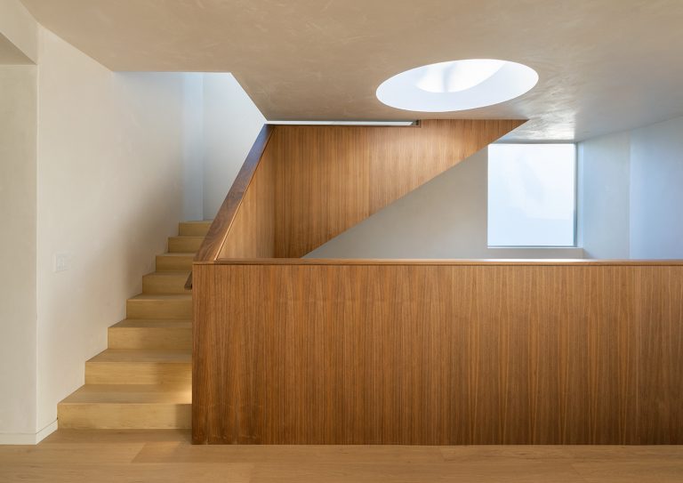Radius House – Leseno stopnišče pod okroglim strešnim oknom.