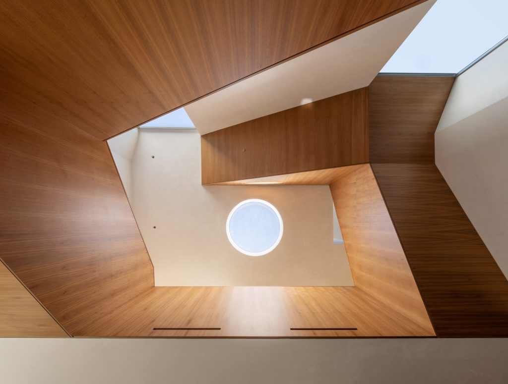 Radius House – Pogled navzgor skozi z lesom obložen atrij.
