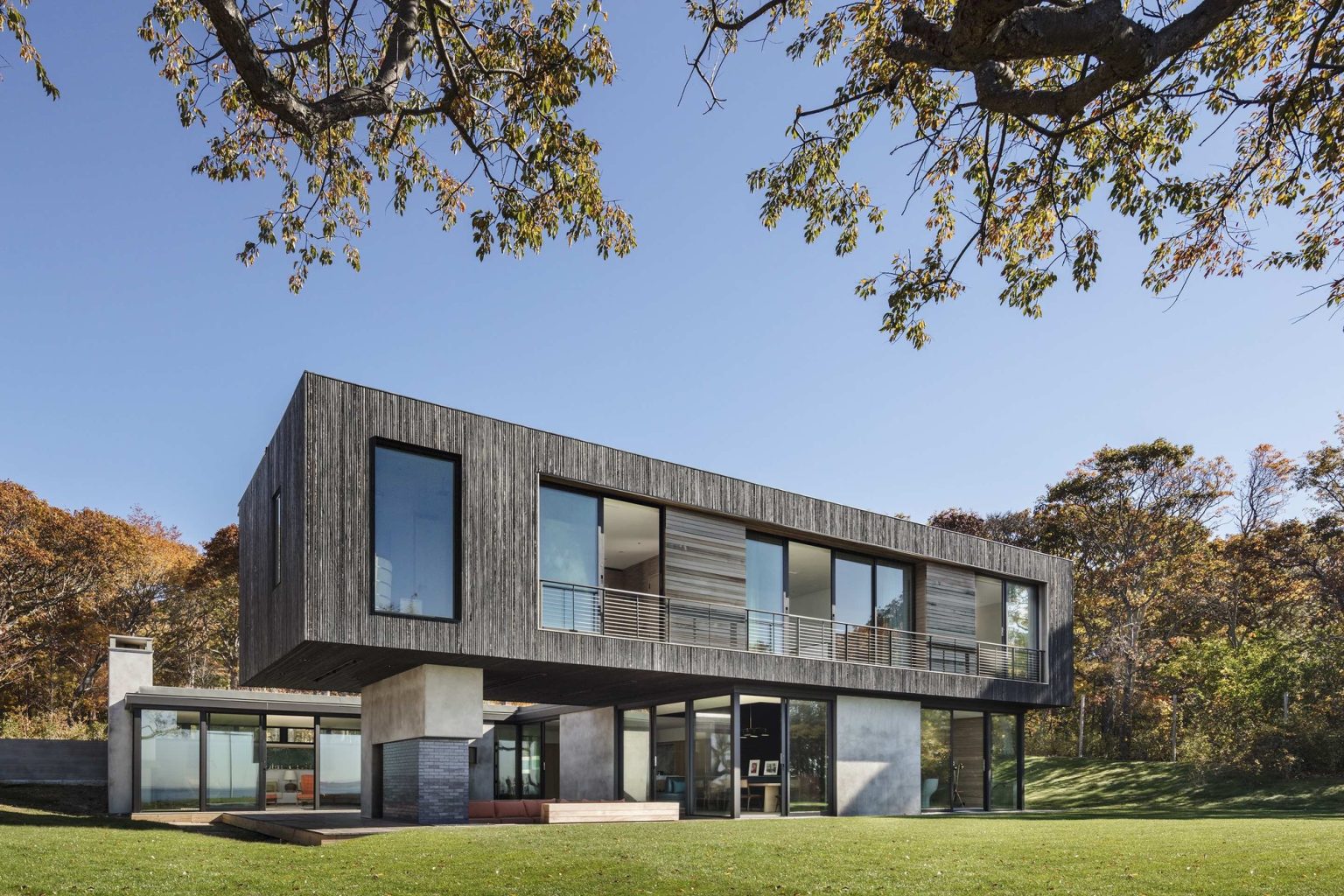 Shore House – Konzolni zgornji volumen nad zastekljenim pritličjem.