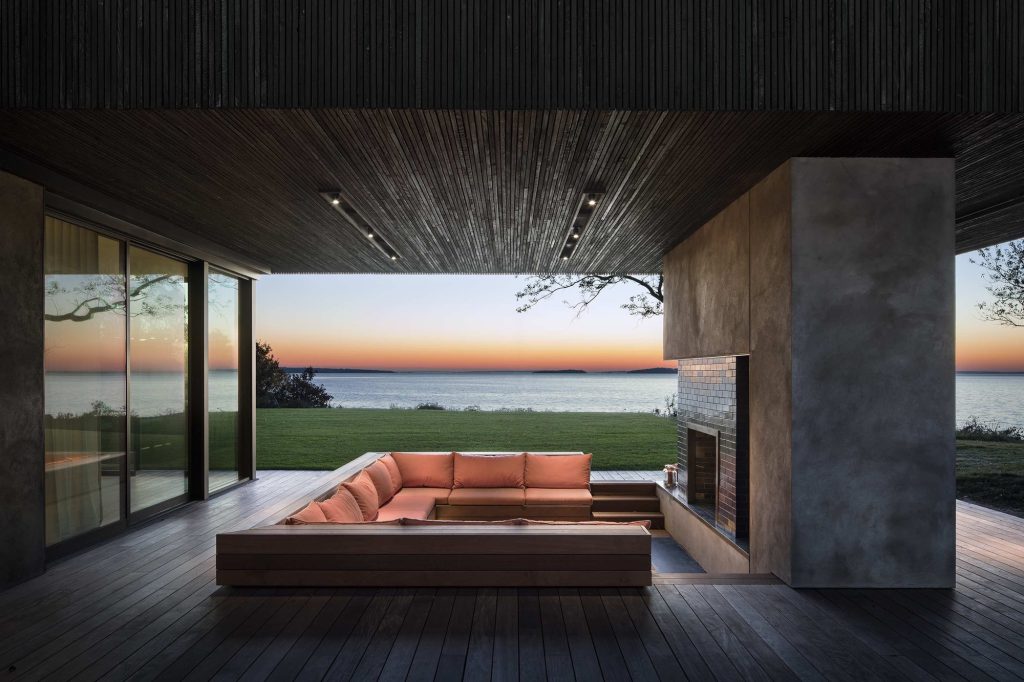 Shore House – Pokrito zunanje sedišče z ognjiščem in pogledom na vodo.