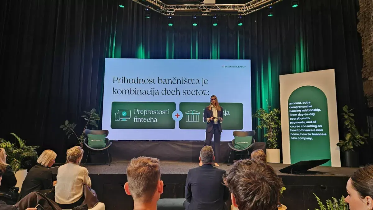 Govornica na odru na dogodku Intesa Sanpaolo Bank pred predstavitvenim zaslonom.